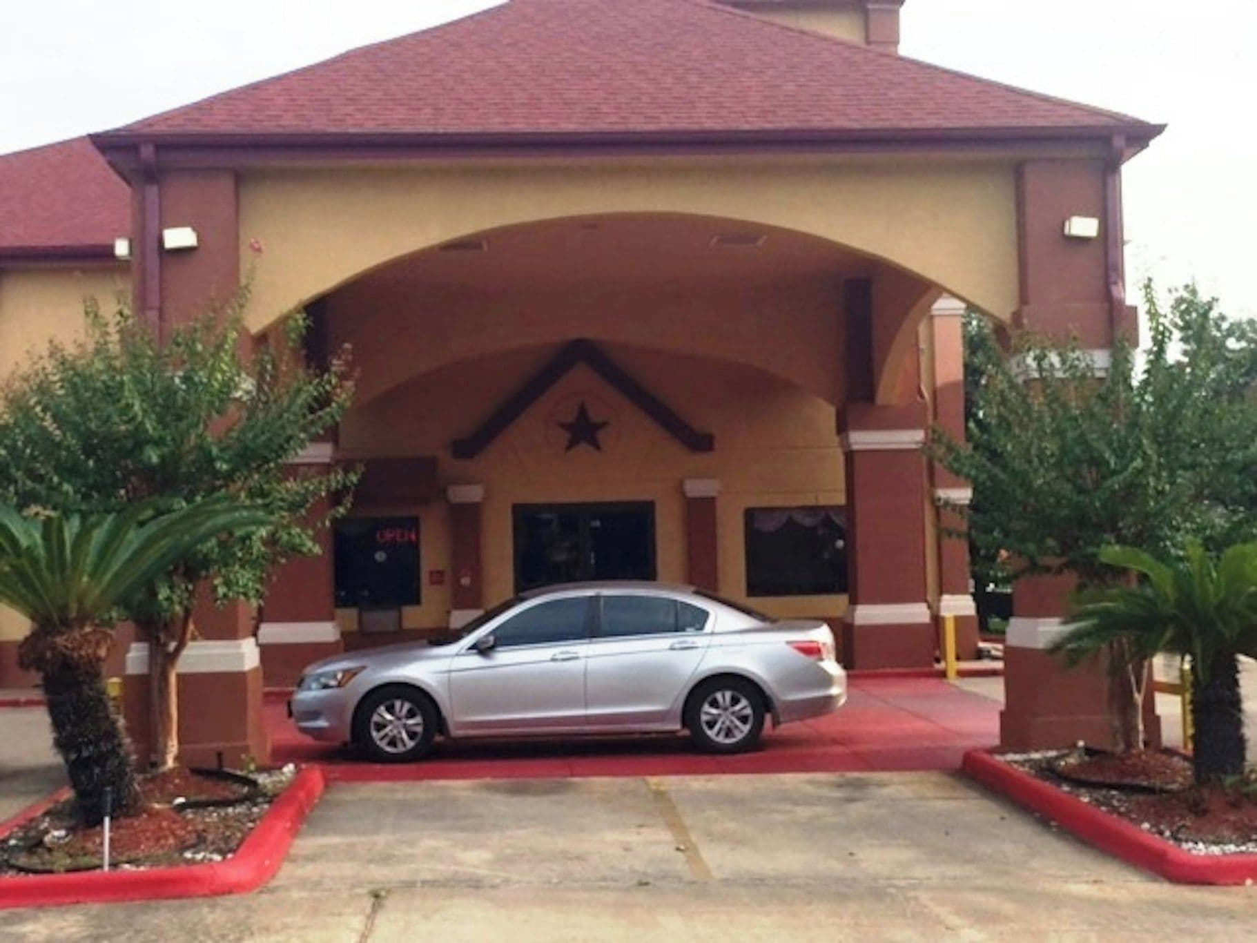 Un bâtiment avec un toit rouge, un emblème en forme d’étoile et une voiture garée devant.