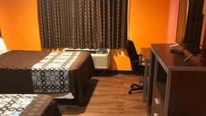 Ein Hotelzimmer mit zwei Betten, einem Schreibtisch, einem Stuhl und einem Fernseher.