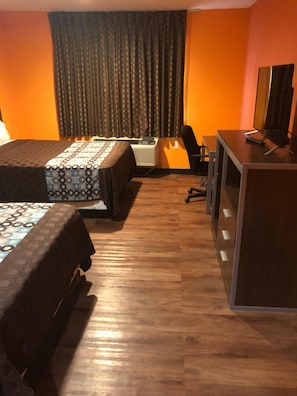 Ein Hotelzimmer mit zwei Betten, einem Schreibtisch, einem Stuhl und einem Fernseher.
