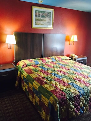 Ein Hotelzimmer mit einem großen Bett, zwei Nachttischen, einer Lampe und einem Gemälde an der Wand.