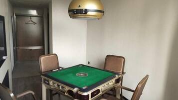 Una habitación con mesa de billar, cuatro sillas y una lámpara colgante.