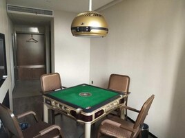 Una habitación con mesa de billar, cuatro sillas y una lámpara colgante.