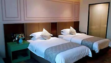 Una habitación de hotel con dos camas, una mesita de noche y un armario espacioso.