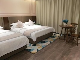 Habitación de hotel con dos camas, una mesita con sillas y una alfombra estampada.