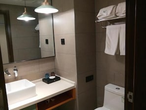 Un bagno con lavandino, specchio e porta asciugamani bianchi.