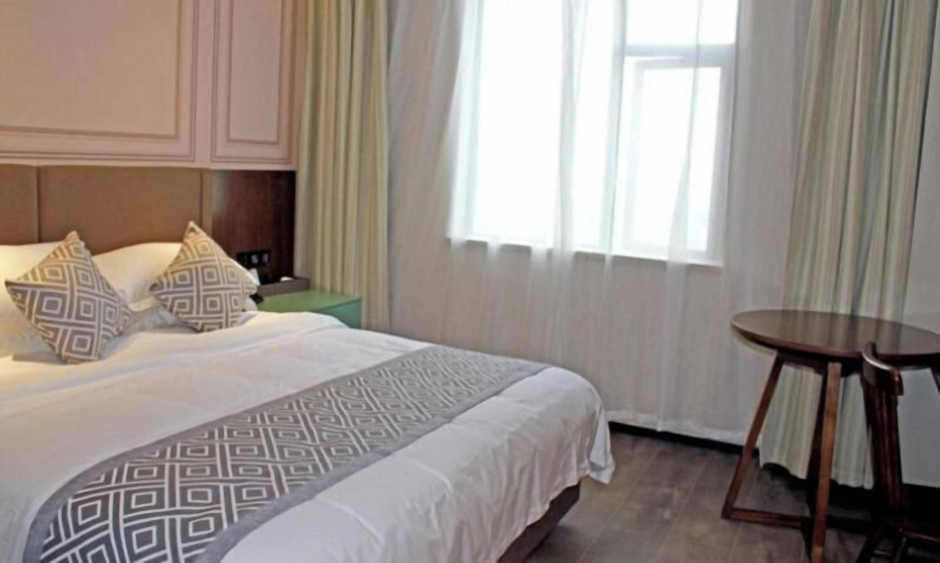 Een hotelkamer met een groot bed, twee nachtkastjes en een raam met gordijnen.