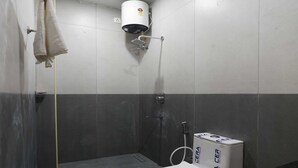 A small bathroom with a toilet, a shower, and a towel rack. - Collection O Thirukadaiyur Bus Terminal (Tarangambadi)