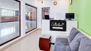 A reception area with a reception desk, a computer, and a couch. - Collection O Thirukadaiyur Bus Terminal (Tarangambadi)