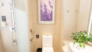 Ein modernes Badezimmer mit einer gläsernen Duschkabine, Toilette und Waschbecken mit Pflanze.