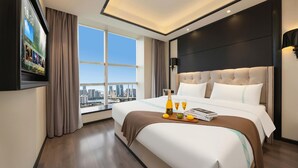 A hotel room with a large bed, a city view, a flat-screen TV, and a bottle of champagne on the bedside table. - Xana Hotelle (Nanchang)