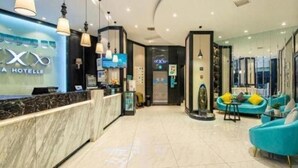 A hotel reception area with a marble counter, a reception desk, and a seating area with blue chairs. - Xana Hotelle (Nanchang)