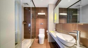 A modern bathroom with a glass-enclosed shower, a white toilet, and a large white sink with a mirror above it. - IU Hotel (Suzhou)