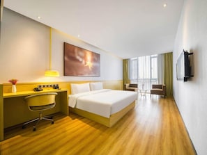 Ein Hotelzimmer mit Bett, Schreibtisch, Stuhl und Fernseher.