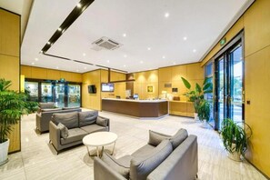 Un moderno vestíbulo de hotel con mostrador de recepción, zona de estar y grandes ventanales.