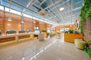 Un espacio interior moderno con mostrador de recepción, zona de estar y techo con diseño de cuadrícula.