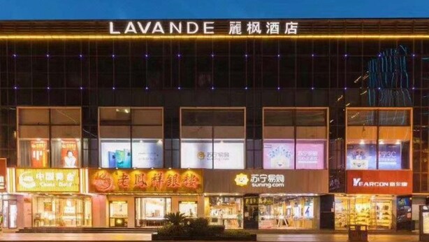 A hotel with multiple illuminated storefronts, including a prominent sign for 'LAVANDE' and other visible business signs. - Lavande Hotel (Suzhou)