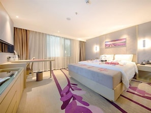 A hotel room with a bed, bedside table, desk, chair, and a large window with curtains. - Lavande Hotel (Suzhou)