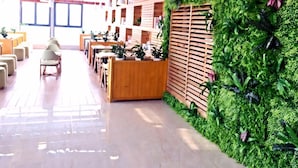 A modern interior with a reception desk, seating area, and a green wall with plants. - Lavande Hotel (Suzhou)