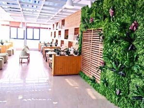 A modern interior with a reception desk, seating area, and a green wall with plants. - Lavande Hotel (Suzhou)