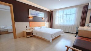Quarto de hotel com cama, mesa de cabeceira, cadeira e escrivaninha com cadeira.