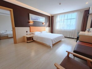 Una habitación de hotel con cama, mesita de noche, silla y escritorio con otra silla.