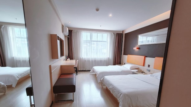 Quarto de hotel com duas camas, uma escrivaninha, uma cadeira, um espelho e uma janela com cortinas.