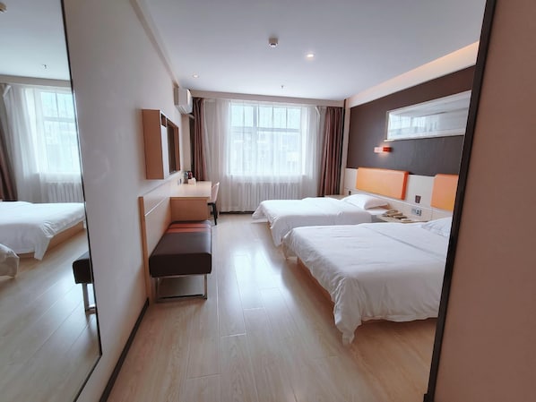 Habitación de hotel con dos camas, un escritorio, una silla, un espejo y una ventana con cortinas.
