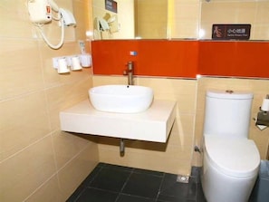 Un baño con un lavamanos blanco, un inodoro y un secador de pelo en la pared.