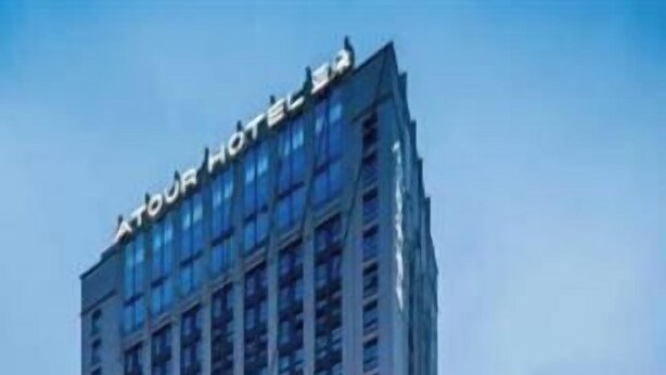 Ett högt hotell med en framträdande skylt högst upp, flera våningar och en väl upplyst entré.