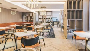 En modern restaurang med höga bord och stolar, hängande lampor och ett fiskbensmönstrat golv.