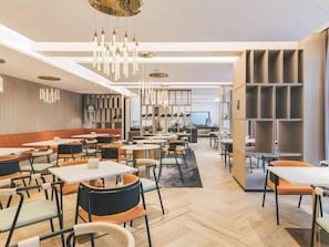 Ein modernes Restaurant mit hohen Tischen und Stühlen, Pendelleuchten und einem Fischgrätparkett.