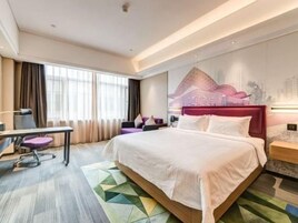A modern hotel room with a large bed, a desk, and a chair.