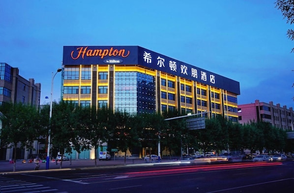 A hotel with a prominent 'Hampton by Hilton' sign, multiple floors, and a modern architectural design.
