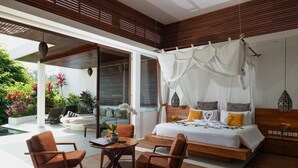 Ein modernes Schlafzimmer mit Baldachinbett, einer Sitzecke mit Sesseln und Blick auf einen Garten.