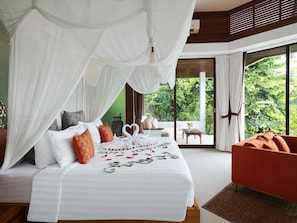 A bedroom with a canopy bed, a view of greenery outside, and a red armchair. - Cahaya Indah Villas Ubud (Ubud)