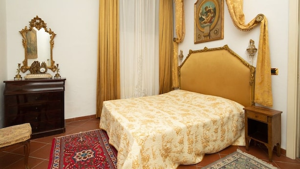 Ein Zimmer mit einem Bett, einem Schminktisch, einem Spiegel und einem Bild an der Wand.