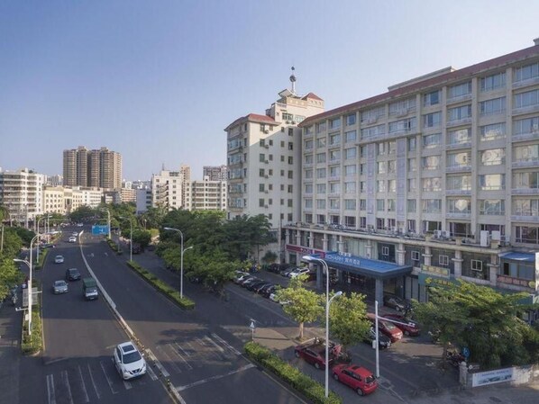 Un hotel de varios pisos con estacionamiento al frente, rodeado de otros edificios.