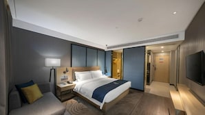 A modern hotel room with a bed, bedside table, lamp, and a flat-screen TV. - Echarm Hotel (Haikou)