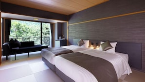 Ein modernes Hotelzimmer mit einem großen Bett, einer Sitzecke mit einer Bank und Blick ins Freie.