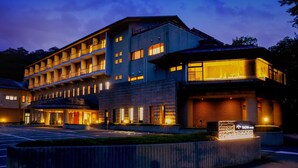 Ein mehrstöckiges Hotel mit modernem Design, das einen markanten Eingang und eine gut beleuchtete Fassade besitzt.