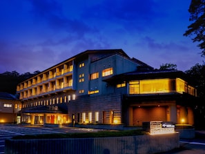 Ein mehrstöckiges Hotel mit modernem Design, das einen markanten Eingang und eine gut beleuchtete Fassade besitzt.