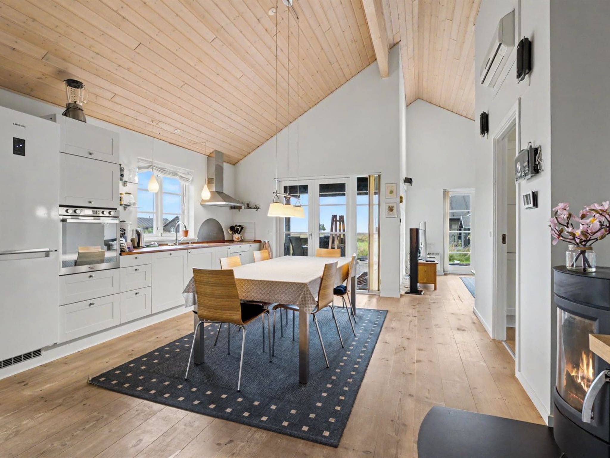 A modern kitchen with white cabinets, a dining area with a table and chairs, and a fireplace.