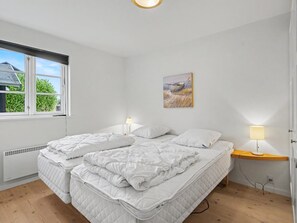 A bedroom with two beds, a window, a painting, and a bedside table with a lamp. - "Gunda" - 150m from the sea by Interhome (Nysted)