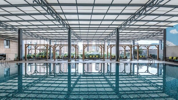 An indoor swimming pool with a clear view of the cityscape through large windows. - Wyndham Garden Kunming High Tech Zone (Kunming)