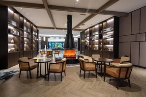 A modern lounge area with a central fireplace, seating, and bookshelves. - Wyndham Garden Kunming High Tech Zone (Kunming)