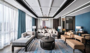 A modern hotel room with a sofa set, a round coffee table, and a dining area with a table and chairs. - Wyndham Garden Kunming High Tech Zone (Kunming)