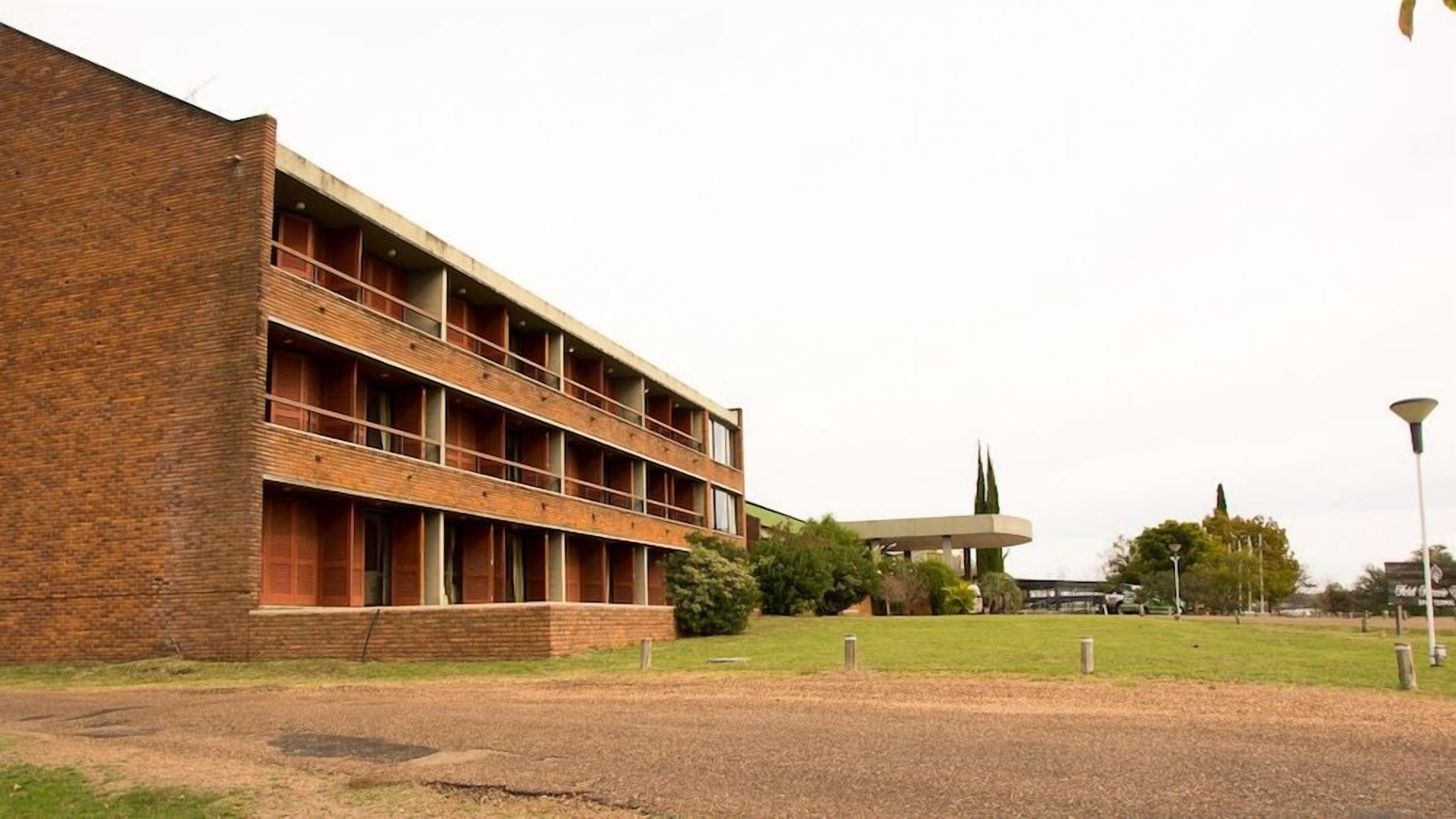 A multi-story building with a brick facade, a flat roof, and a series of windows.