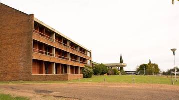 A multi-story building with a brick facade, a flat roof, and a series of windows.