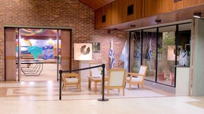 A lobby with a brick wall, glass doors, and a seating area with chairs and tables.