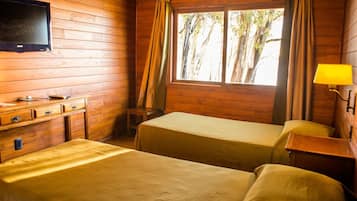 A room with two beds, a wooden dresser, a television, and a window with curtains.